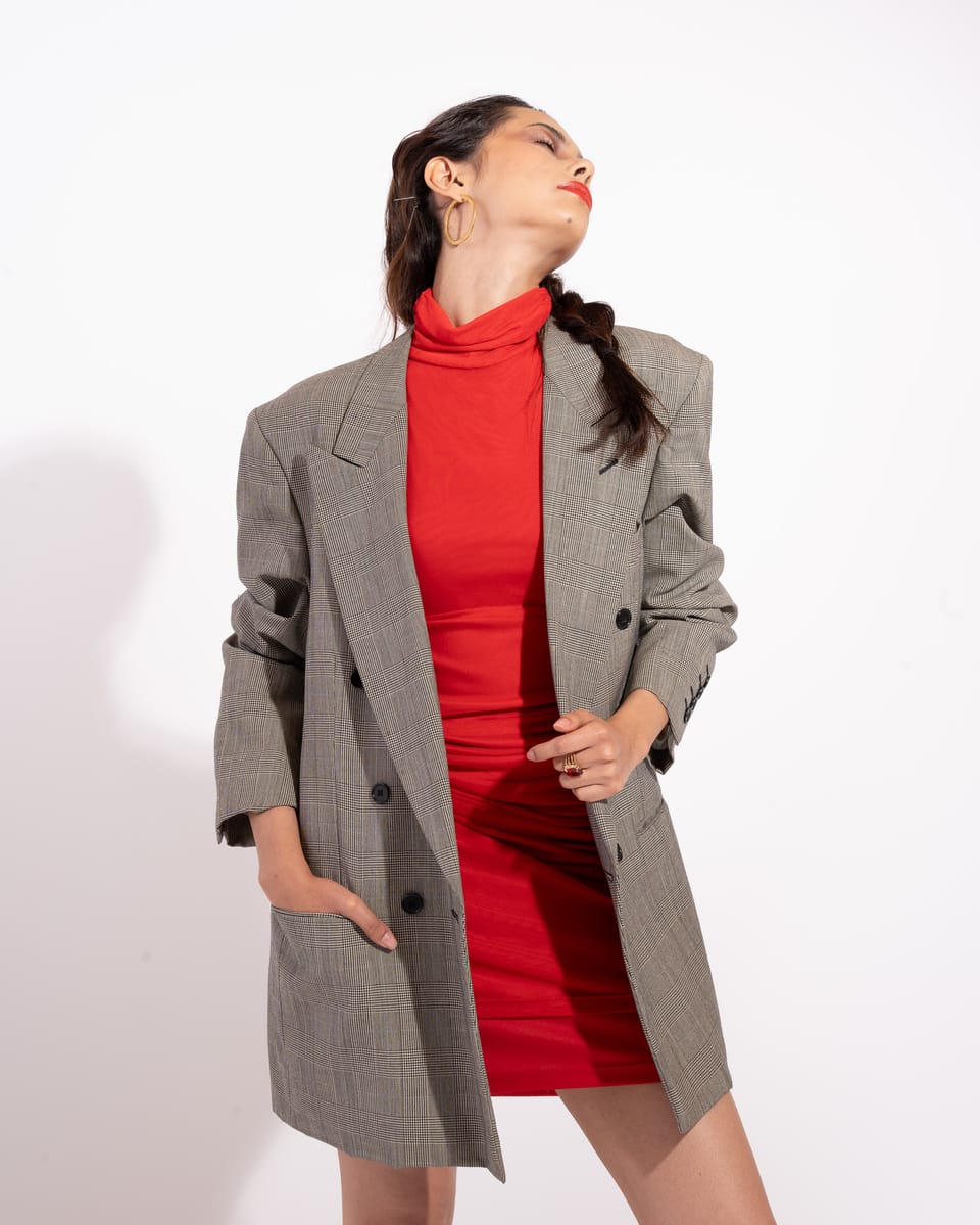Modelo con saco gris y vestido rojo en estudio