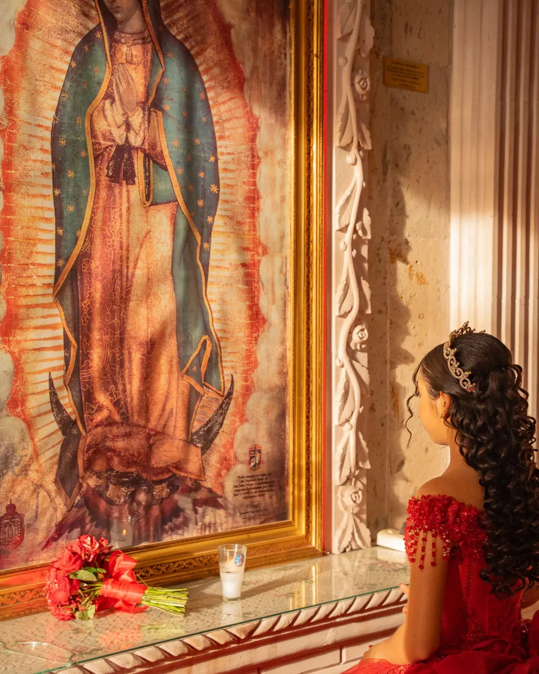 Quinceañera frente a la imagen de la Virgen de Guadalupe con su ofrenda de rosas