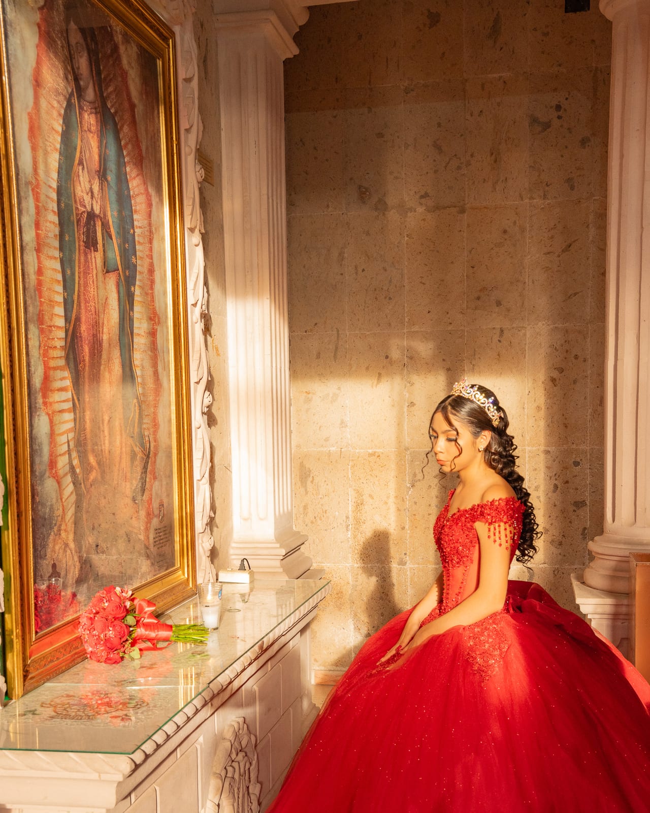 Quinceañera con vestido rojo frente a un mural