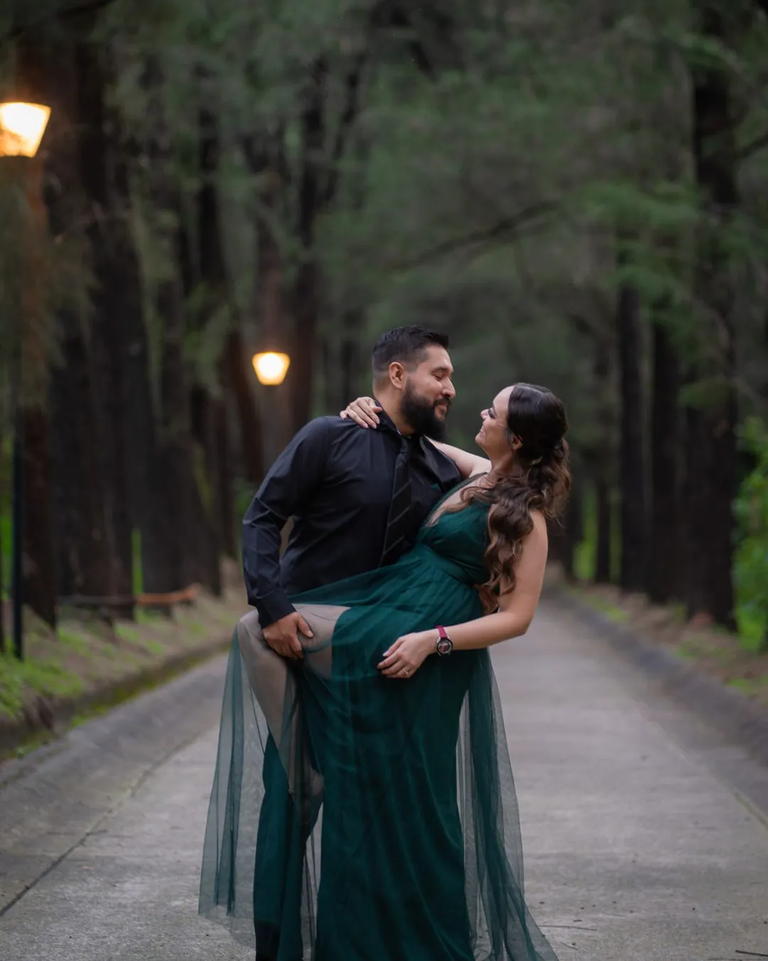 Pareja en un camino del bosque con faroles encendidos