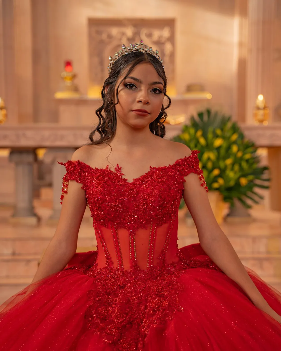 Retrato de quinceañera con vestido rojo frente al altar